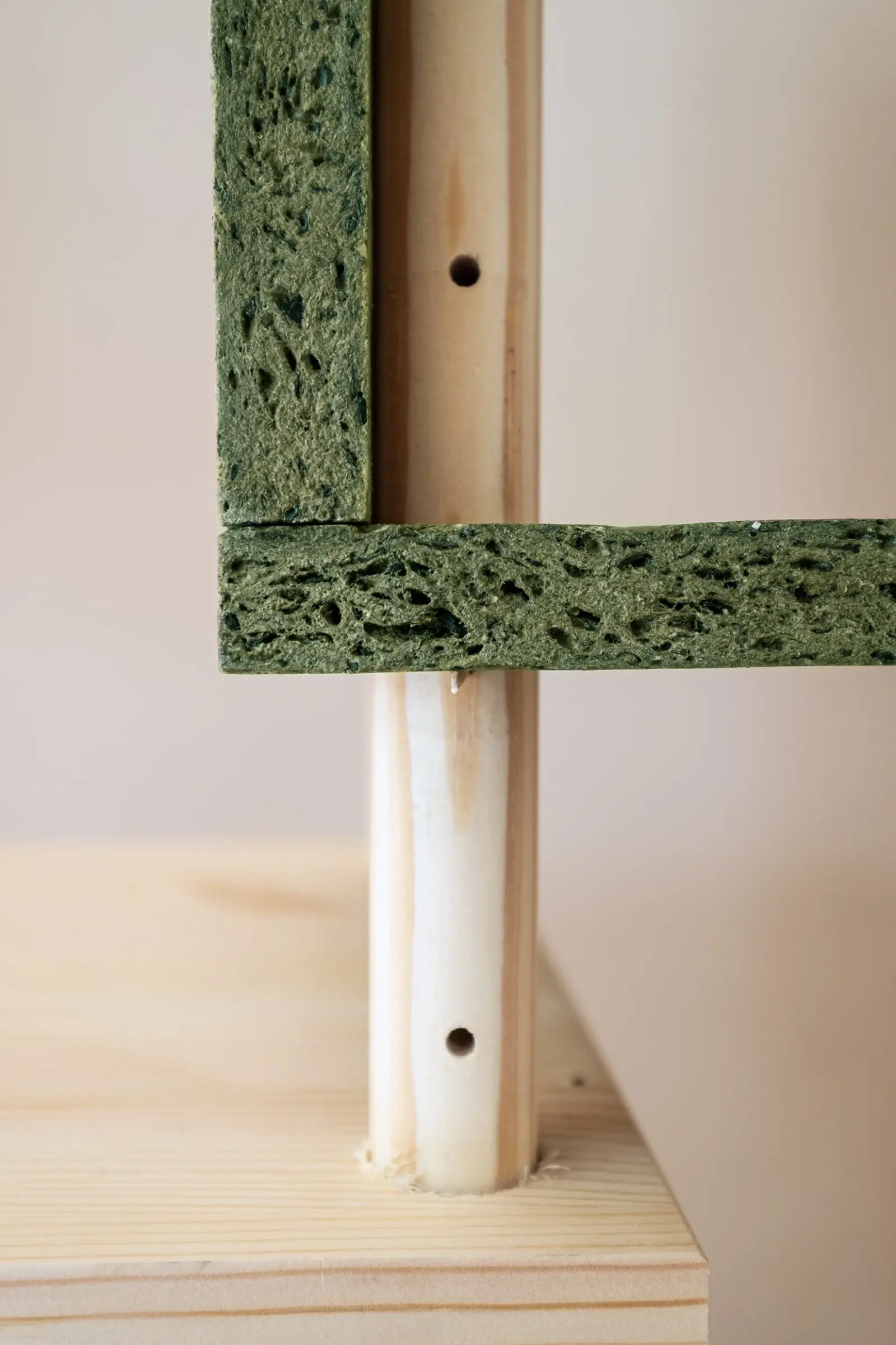 Close-up of a green SeaWood shelf and box meeting a drilled pine frame pole